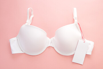 White women's bra with white paper label on pink background