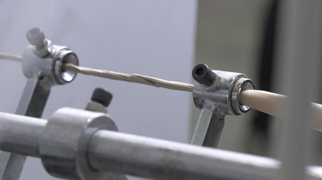 Small cylinders form shape of moving cardboard material. Cardboard factory workshop contains machine for creating thin rope as final product