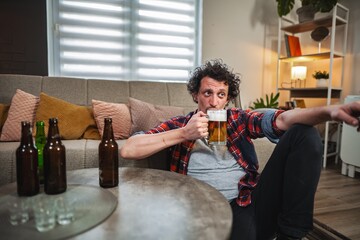 Man drinking beer and watching tv at home