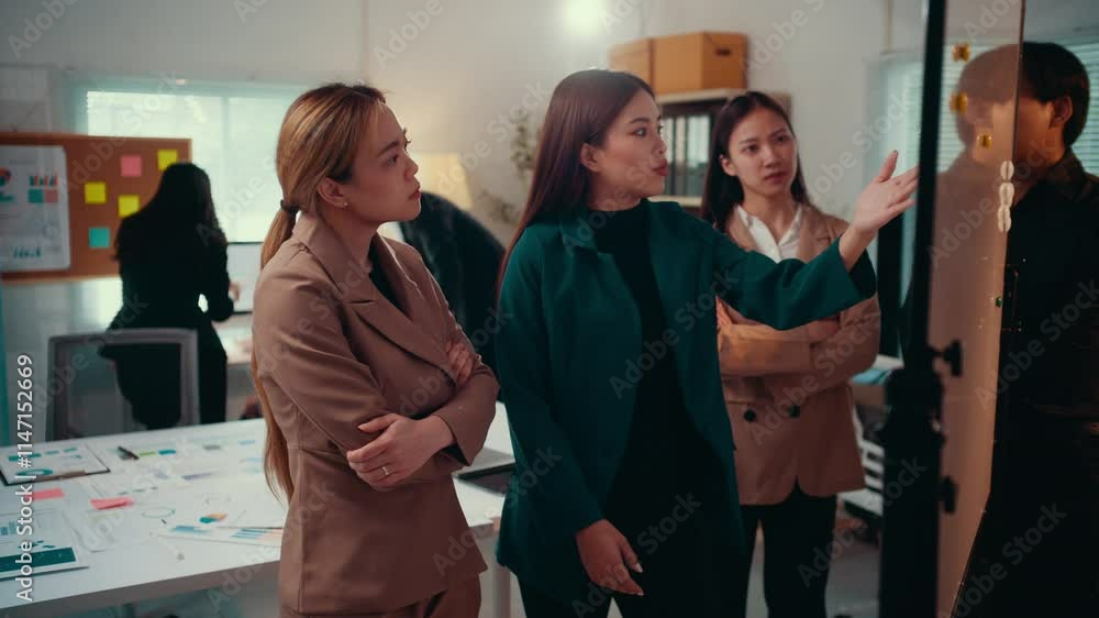 Aufkleber Three asian businesswomen are having a discussion in front of a whiteboard with sticky notes, analyzing data and strategizing for their next business move inside a modern office