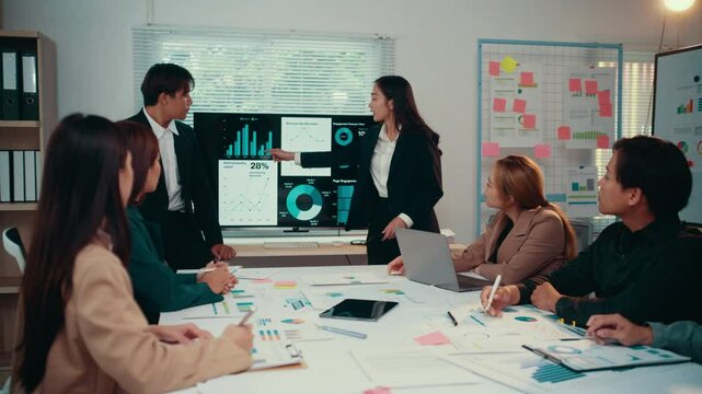 Office workers and managers gather around an interactive screen, actively discussing and analyzing financial charts and data during a productive business meeting