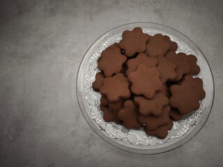 Delicious flower shaped chocolate cookies resting on elegant glass plate christmas time copy space