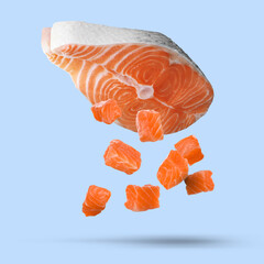 Red fish steak and pieces falling on light blue background