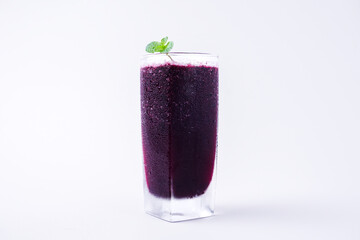 a glass of black grape juice on a white background.