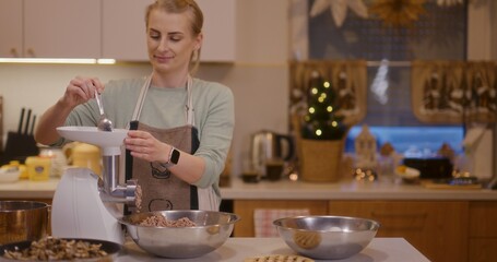 Woman prepares holiday dishes grinding meat in meat grinder