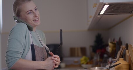 Happy Woman Talking on the Phone While Cooking and Working in the Kitchen