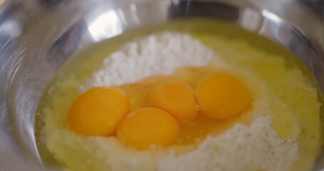 Raw eggs cracked into flour in bowl