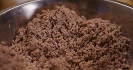 Macro shot of meat cooked and ground in meat grinder in bowl