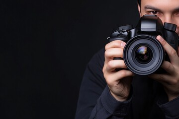 A person holding a camera, ready to take a photograph against a dark background.