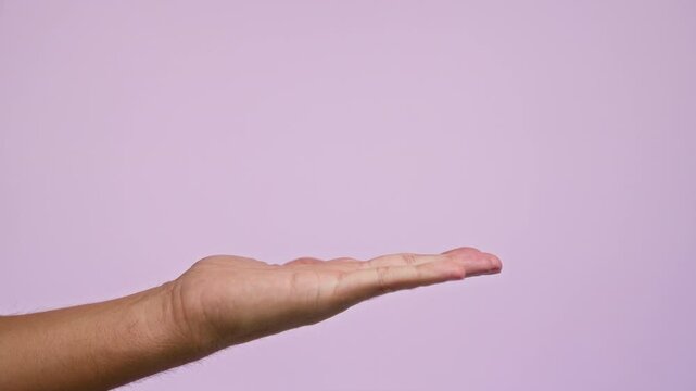 Man pointing at outstretched hand against light pink background suggesting interaction or instruction