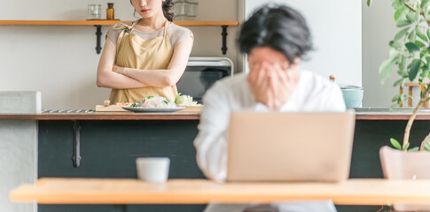 テレワークする夫をキッチンで不機嫌そうに睨む主婦・妻（喧嘩・イライラ・ストレス）  © buritora