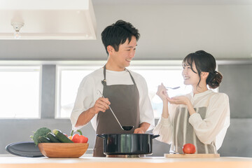 料理を作って味見をする夫婦・カップル・男女（キッチン）
