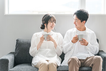 家のリビングのソファでくつろぐ夫婦・カップル・パートナー・家族
