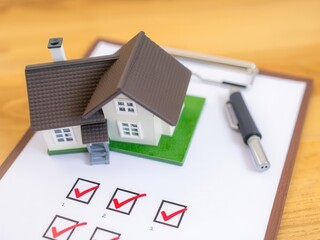 Home inspection checklist on clipboard with miniature house model in background, real estate and home buying concept, home buying, inspection items, red check marks