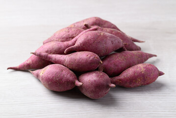 Raw purple sweet potatoes from local farmer market on white table