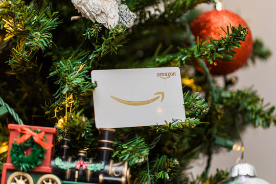 White amazon gift card on a christmas tree surrounded by ornaments 