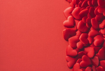 Valentine's Day Background of red fabric hearts scattered across a vibrant red background, leaving ample space for text or design elements