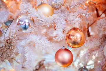 White Christmas tree featuring shiny orange and silver baubles with glittery decorations