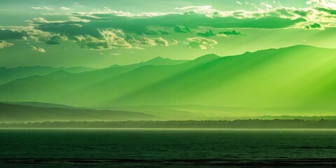 Obraz premium Silhouetted mountain ranges bathed in a vibrant green glow, casting long shadows across a serene, mist-shrouded lake
