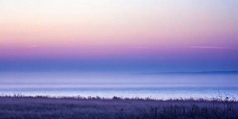 Obraz premium A dreamy and tranquil lakeside landscape at twilight, bathed in soft, pastel hues of pink and blue, with a blanket of mist settling over the water