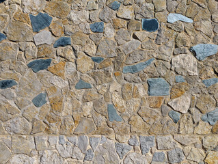 Irregular rustic stone and cement outdoor wall texture or background. Exterior wall cladding with mediterranean natural stones of different colors.	