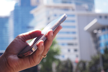 Individual with a smartphone amidst an urban landscape background