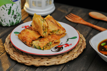 Egg martabak with vinegar sauce is served on a white plate