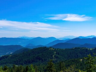 Fototapeta premium A stunning view of vibrant mountains in a natural landscape, featuring lush green trees and a clear blue sky, blue sky, breathtaking, landscape