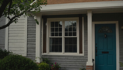 Gray-Sided House with Teal Door and Multi-Paned Window