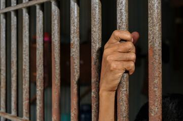 Obraz premium prisoner's hands behind bars with black background