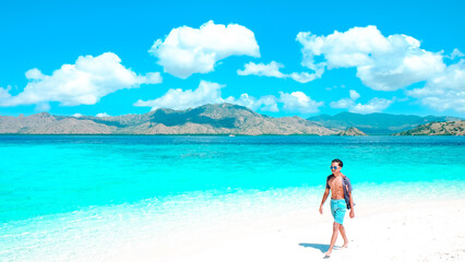 Man walking at the beach shore by the ocean. Summer travel vacation