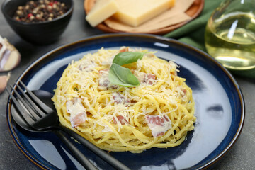 Plate with delicious pasta Carbonara and cutlery on grey textured table, closeup