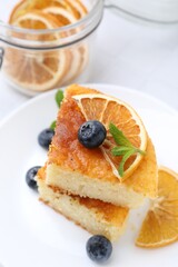 Pieces of delicious semolina cake with blueberries and orange slices on table, closeup