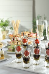 Many different tasty canapes on white table indoors