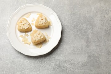 Pieces of delicious sweet semolina halva with almond flakes on light grey table, top view. Space for text