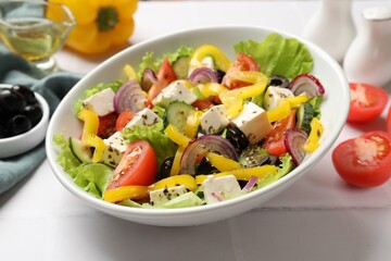 Delicious fresh Greek salad served on white tiled table, closeup