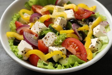 Delicious fresh Greek salad in bowl on table, closeup