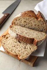 Cut loaf of fresh bread and knife on table, closeup