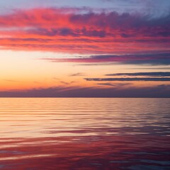 Obraz premium A breathtaking sunset paints the sky with fiery oranges, pinks, and purples, reflected serenely on the tranquil oceans surface. Clouds add depth and texture.