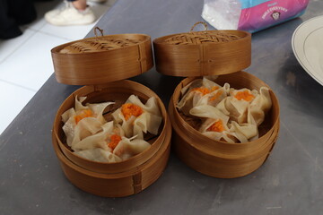 Fresh steamed dim sum served in a traditional bamboo basket neatly arranged with garnish. A classic Chinese dish suitable for any occasion. Suitable for food themes, culinary and Asian cuisine.