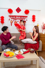 A cheerful Chinese family celebrates Chinese New Year as the parents sing while their daughter...