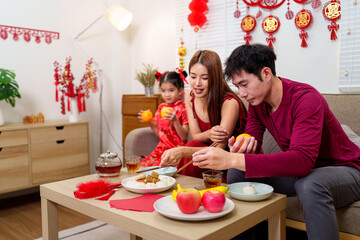 A Chinese family of three arranges a festive dining table to celebrate the Chinese New Year, highlighting cultural traditions and family bonding