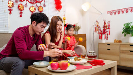 A Chinese family of three arranges a festive dining table to celebrate the Chinese New Year,...