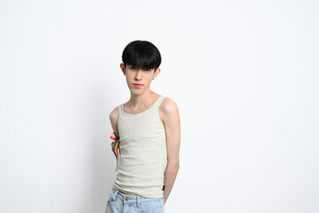 Cute man with rainbow ribbon tied on their arm posing confidently on white background. LGBTQ pride...