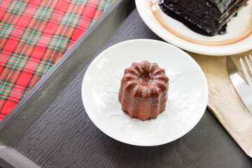 Homemade Canelés and Fudgy brownies on plate, traditional French sweet dessert,selective focus.
