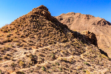 A rocky hillside with a trail leading up to it