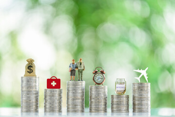 Financial planning, savings for retirement and a secure future : Stacks of coins and various symbolic objects placed on top of them, depicting concepts of healthcare, leisure travel, and retirement.