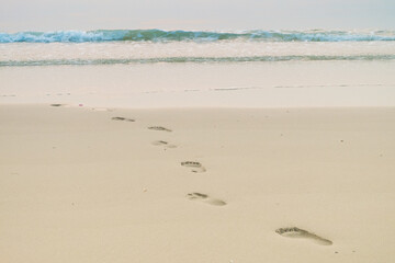 Footprints of human feet on the sand near the water on the beach.