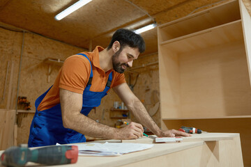 Carpenter measuring with ruler during furniture production process at workshop