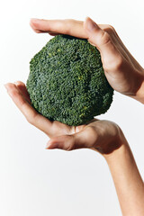 Person holding two pieces of broccoli in each hand